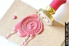 a wax stamp on top of a piece of paper next to a pink rubber seal