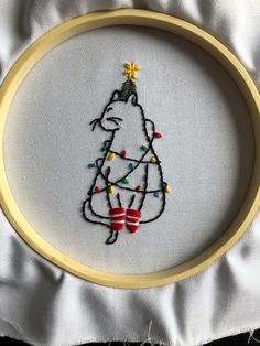 a cross stitch christmas ornament with a hippo holding a lite up tree