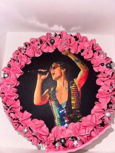 a cake decorated with pink icing and flowers in the shape of a woman singing into a microphone