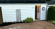 a small white shed with a door and window on the side of it that is open