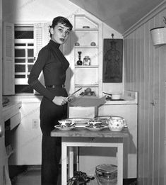 a woman in a black dress standing next to a table