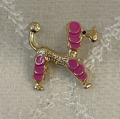 a pink dog brooch sitting on top of a white cloth