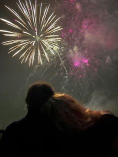 fireworks are lit up in the night sky with people looking at them and taking pictures