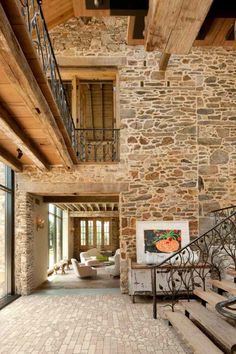 the inside of a house with stone walls and wooden steps leading up to an open floor plan