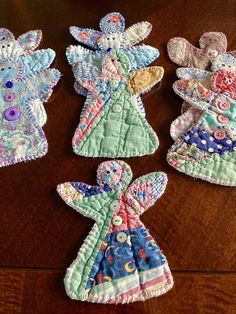 three handmade angel ornaments sitting on top of a wooden table