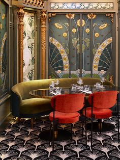 a fancy dining room set up with red chairs and round table in front of an ornate glass door