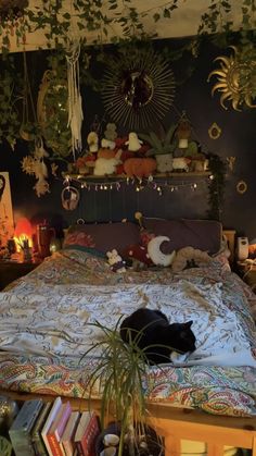 a black cat laying on top of a bed in a room with lots of plants