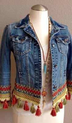 a white mannequin wearing a jean jacket with tassels and beads on it