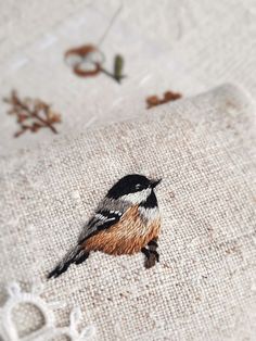 a small bird is embroidered onto a piece of linen