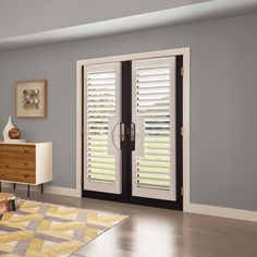 a living room with white shutters on the doors and wooden furniture in front of it