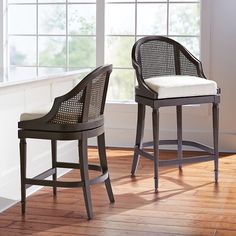 two chairs sitting next to each other on top of a hard wood floor in front of a window