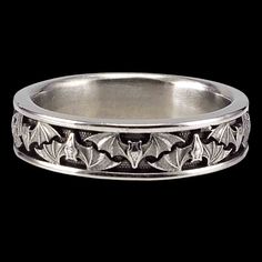 a silver ring with leaves and flowers on the inside, in front of a black background