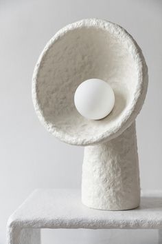 a white sculpture with an egg in it