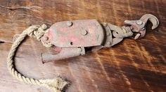 an old, rusty hook and rope on a wooden table