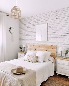 a bedroom with white brick walls and wooden headboard