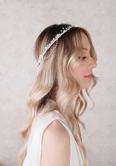 a woman with long blonde hair wearing a headband made of pearls and leaves on her head