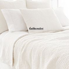 a bed with white linens and pillows on it that have embroidered name pillow cases