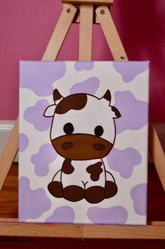 a painting of a cow sitting on top of a wooden easel in front of a pink wall