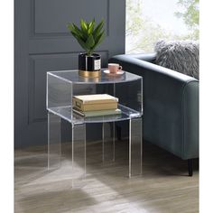 a clear end table with books on it and a potted plant in the corner