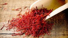 a wooden spoon filled with red cranberries on top of a wooden table next to a pile of dried cranberries