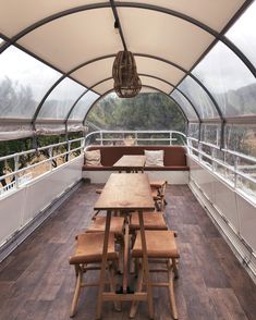 a wooden table sitting under a glass roof