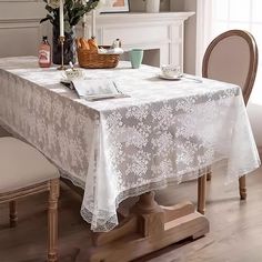 a white table cloth on top of a wooden table next to a vase with flowers