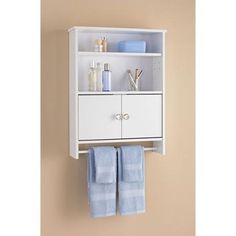 a white bathroom cabinet with towels hanging from it's sides and two blue towels on the bottom shelf