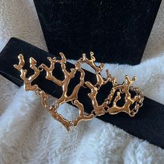 a gold brooch sitting on top of a black velvet belt