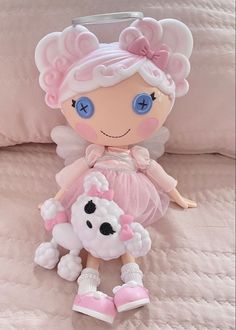 a stuffed animal doll is sitting on a bed with pink and white sheets in the background