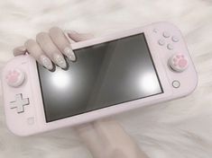 a person holding a pink nintendo wii game controller in their hand with her nails on it