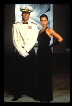 a man and woman in formal wear standing next to each other with their arms around one another