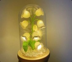 a glass dome with flowers in it on top of a wooden stand next to a wall