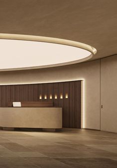 an empty lobby with a reception table and lights on the wall behind it in front of a circular ceiling light