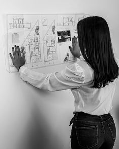 a woman standing in front of a white board with drawings on it and writing on the wall