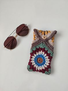 a crocheted case next to sunglasses on a white surface