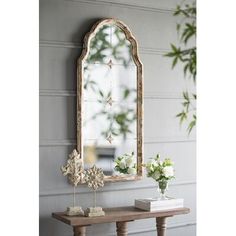 a mirror sitting on top of a wooden table next to a vase filled with flowers