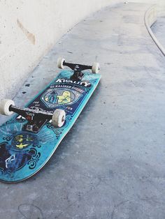 a blue skateboard laying on the ground next to a wall