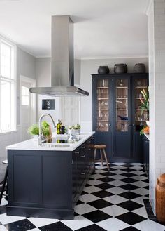 a kitchen with black and white checkered flooring on the walls, an island in the