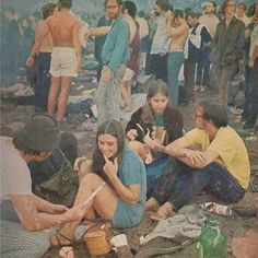 a group of people sitting on top of a field next to each other eating food