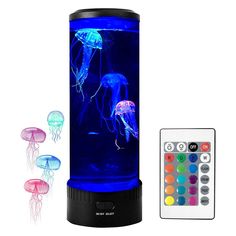 three jellyfish in an aquarium with remotes and color changing lights next to it