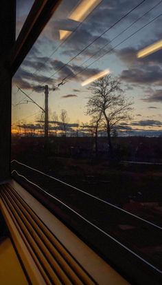 the sun is setting behind power lines as seen from a window in a passenger train