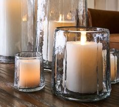 three candles sitting on top of a wooden table next to glass containers filled with water