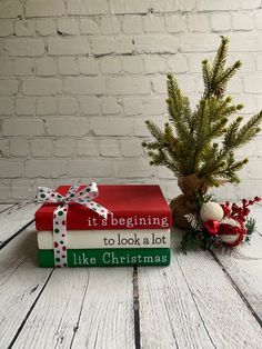 there is a christmas tree next to two books on the table with it's presents