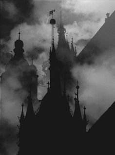 black and white photograph of the top of a building with spires in foggy weather