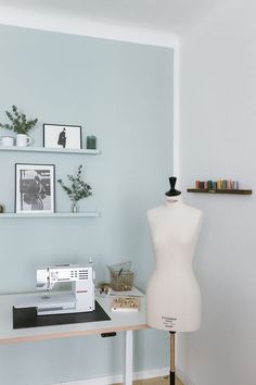 a sewing machine sitting on top of a wooden table next to a white mannequin