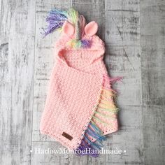 a crocheted pink sweater with multicolored pom poms on it