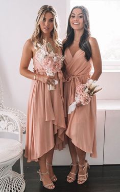 two beautiful women standing next to each other in front of a white chair and window