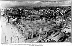 an old black and white photo of a building under construction in the middle of town