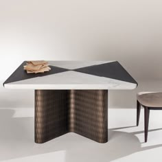 a white table with black and gold designs on it, sitting next to a chair