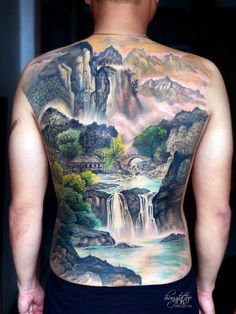 the back of a man with a waterfall and mountains on his back